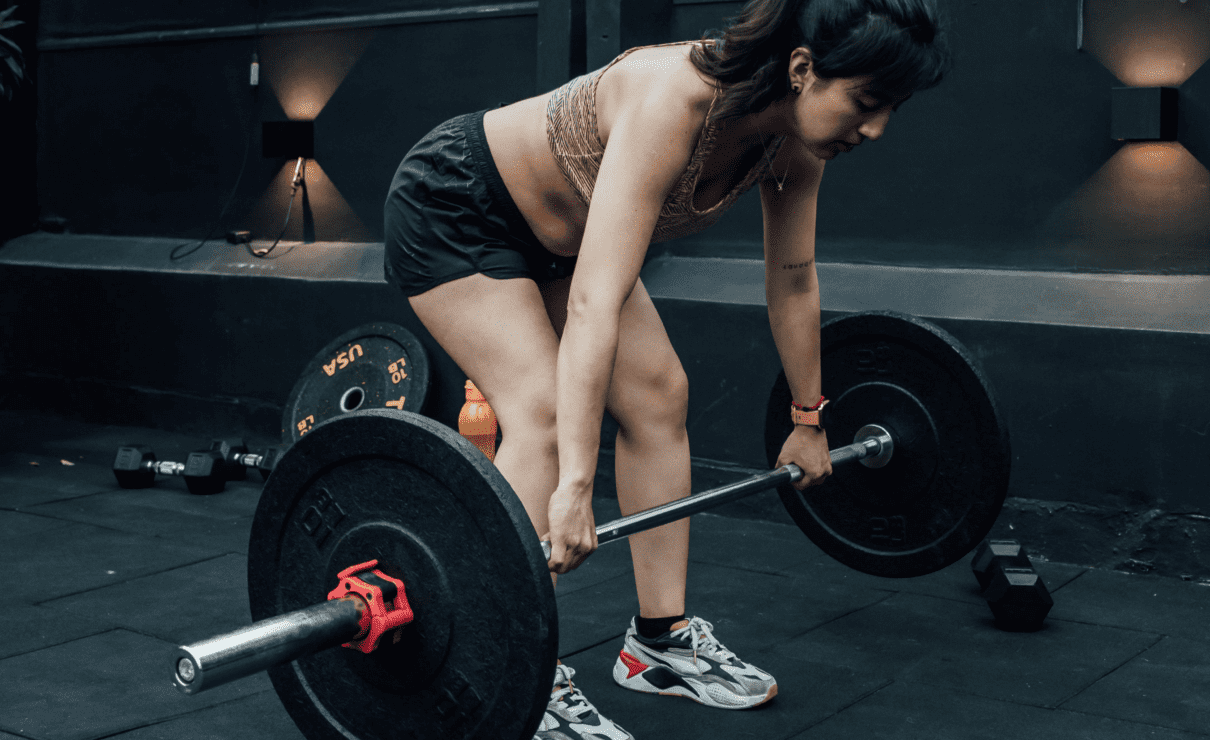 chica haciendo el ejercicicio de peso muerto en el gimansio