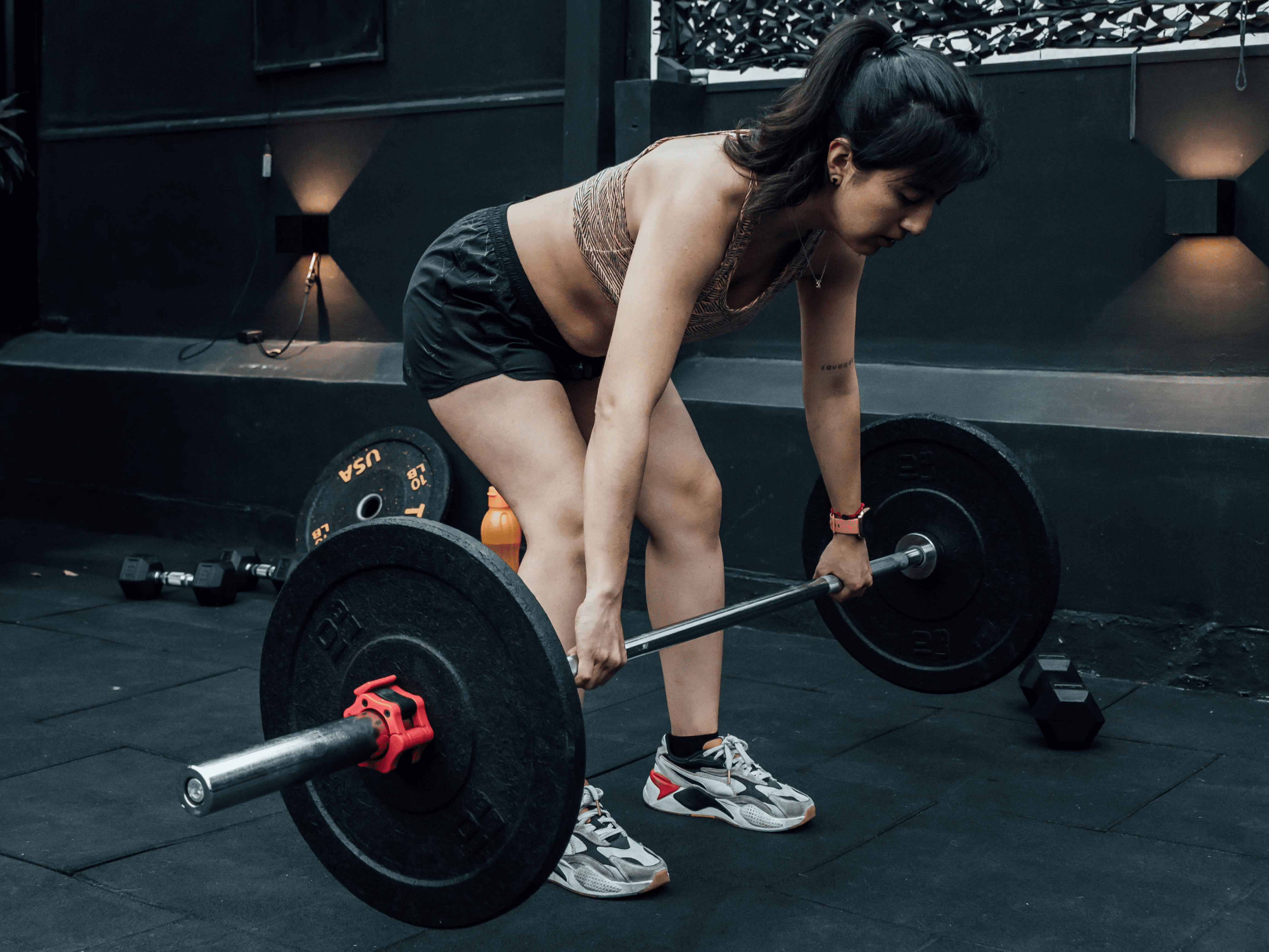 mujer haciendo peso muerto con una barra en el gimnasio