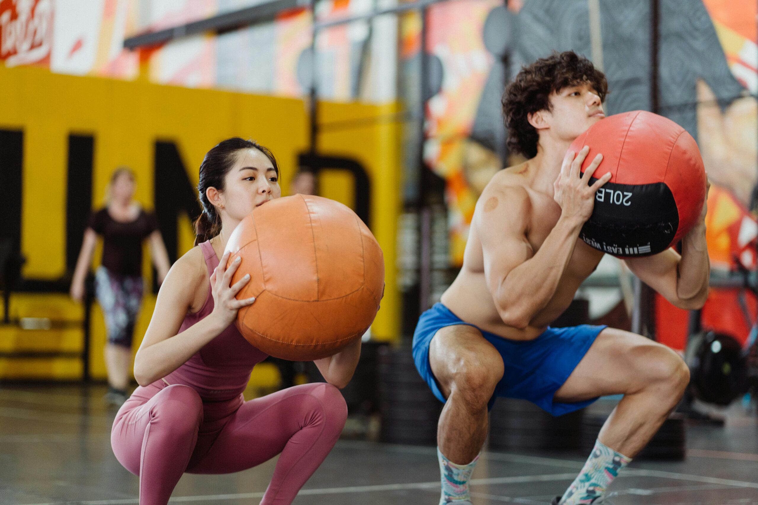 Una pareja haciendo sentadillas con peso en un gimnasio